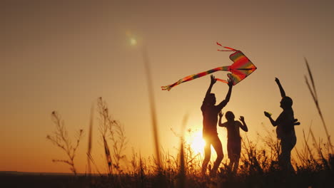Glückliche-Familie,-Die-Bei-Sonnenuntergang-Mit-Einem-Drachen-Spielt-Mama-Papa-Und-Tochter-Sind-Glücklich-Zusammen-4k-Video