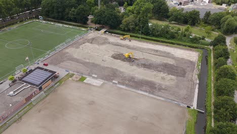 Wide drone shot showing multiple excavators working together to prepare a sports field for grass installation
