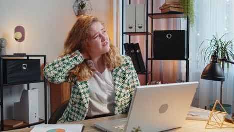 Business-woman-suffers-from-spine-neck-muscle-pain-at-home-office-workplace-working-on-laptop