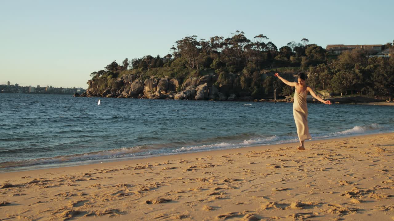 아름다운 일몰 동안 긴 드레스를 입고 해변을 따라 걷는 젊은 지중해 여성의 넓은 사진