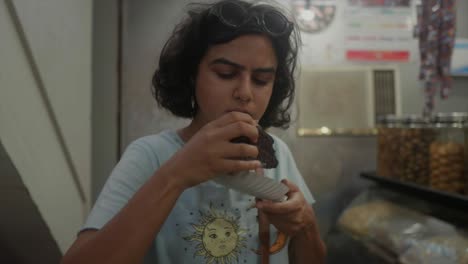 An-Indian-young-girl-indulges-in-a-delightful-cake-tasting-moment-at-a-supermarket