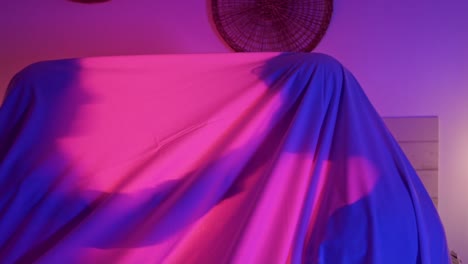 Dolly-shot-of-2-people-under-a-white-sheet-with-a-vibrant-pink-light