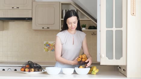 woman puts ripe fruit in a plate in the kitchen woman puts ripe fruit in a plate in the kitchen vegetarianism healthy eating ecobags ecology