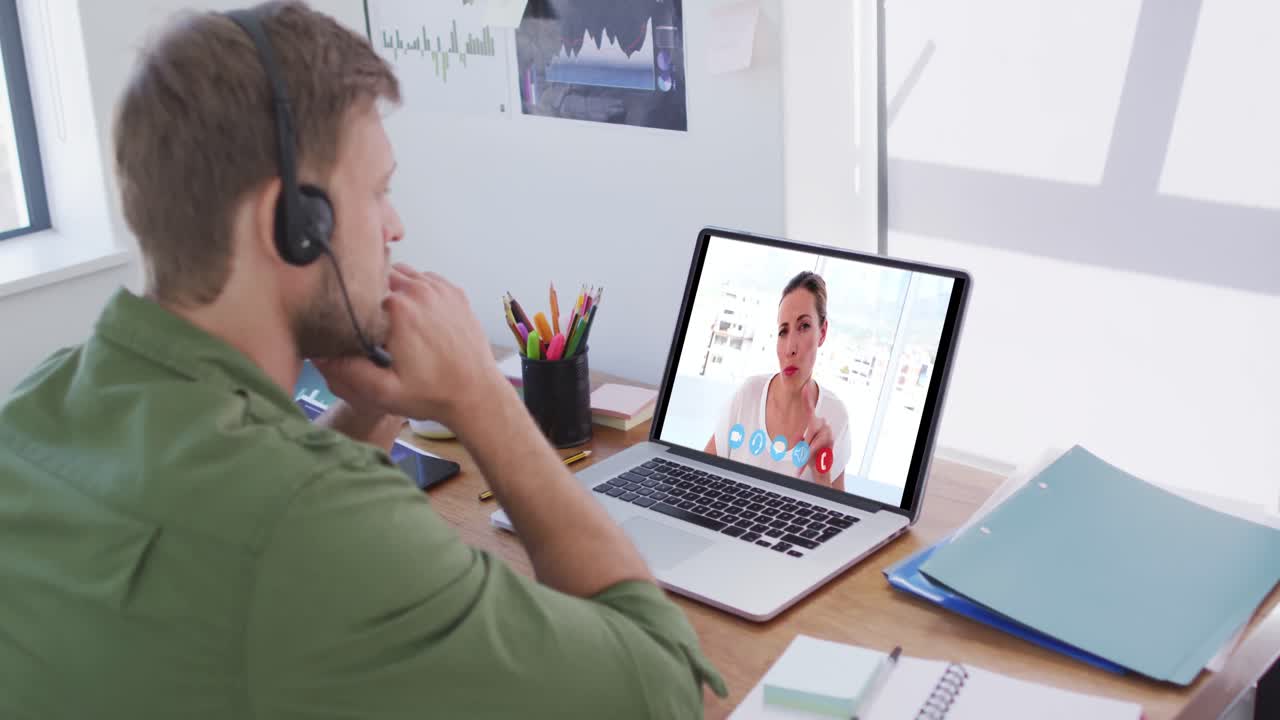 Kaukasisk mand bruger bærbar computer og telefonheadset på videoopkald med en kvindelig kollega.