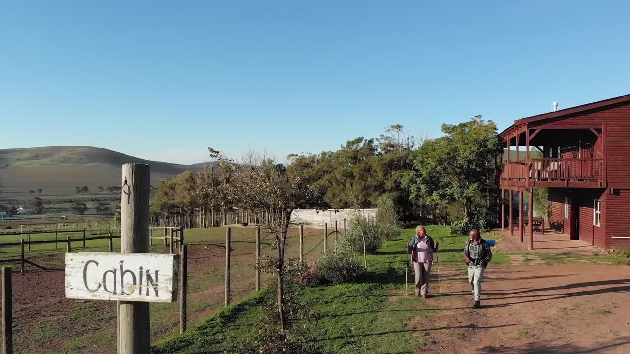 pareja de ancianos afroamericanos con mochilas caminando en la naturaleza soleada, cámara lenta