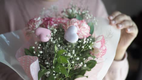 woman holding a beautiful pink flower bouquet with hearts