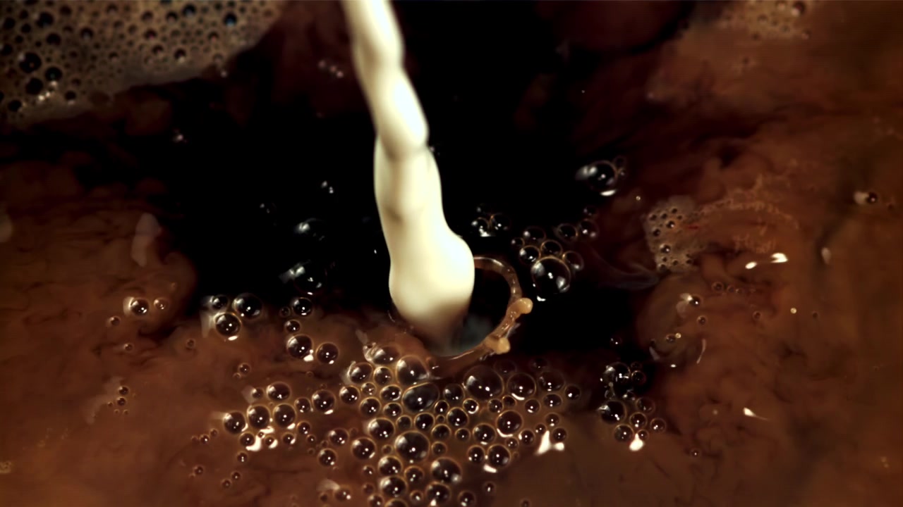 Latte che si versa e si mescola nel caffè scuro al rallentatore
