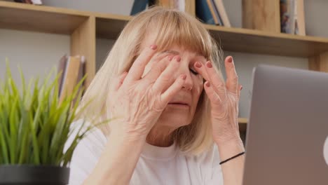 tired old woman in casual clothes working with laptop at home tired old woman in casual clothes working with laptop at home