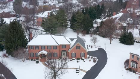 large brick mansion covered in winter snow and decorated for christmas holidays