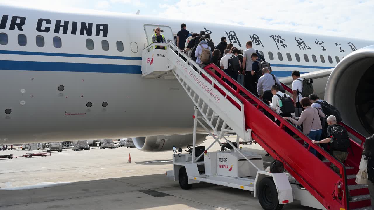 Boarding passengers walk up the stairs to an Air China plane on the runway at Beijing International Airport, China.