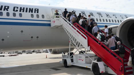 boarding passengers walk up the stairs to an air china plane on the runway at beijing international airport, china.