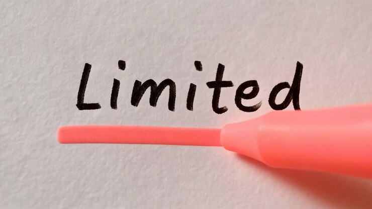 Close-up of a red marker tip writing the word Limited on plain white paper, with soft even lighting and a clean minimal background