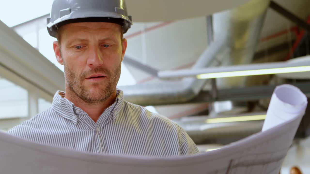 Male architect looking at blueprint 4k