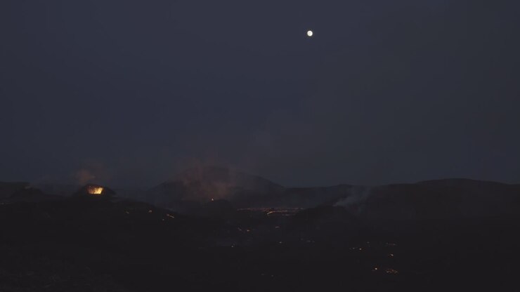 Luna piena sopra un'eruzione vulcanica, Islanda, cinematografico.
