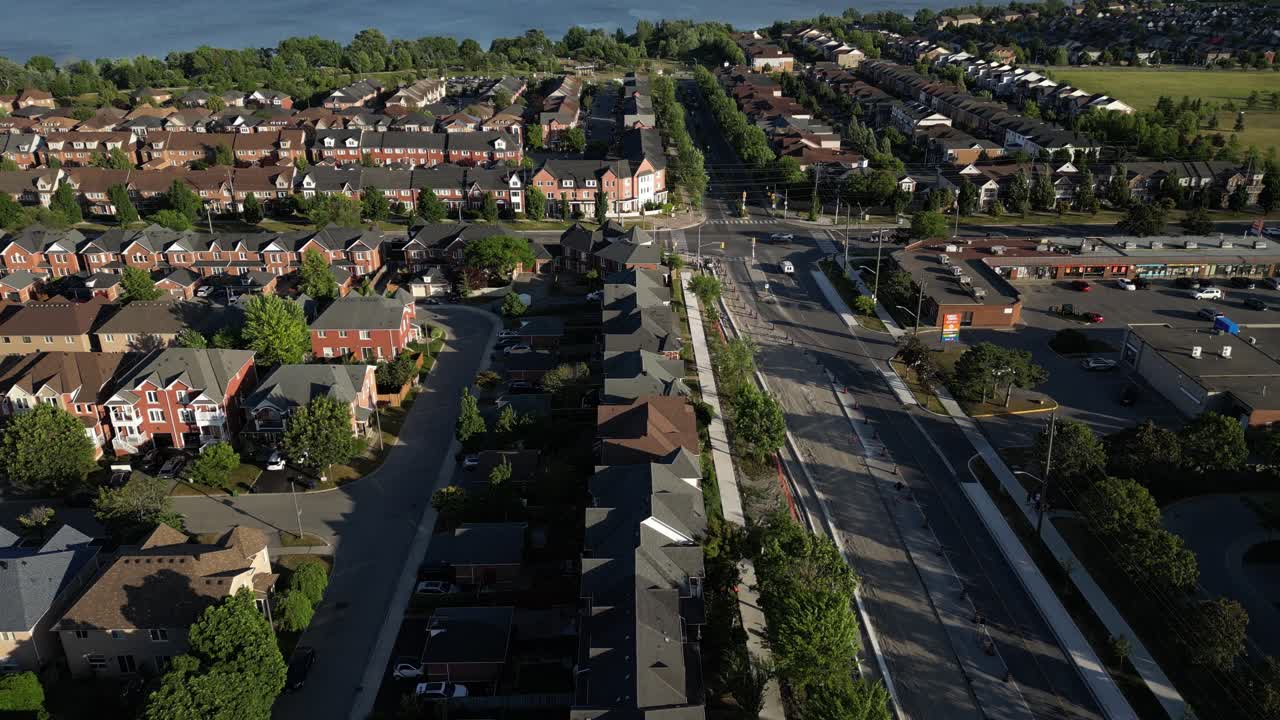 Aerial view over suburban homes in Pickering near Rouge Beach, overlooking Lake Ontario under a calm blue sky with a white sailboat in the distance