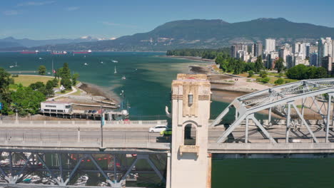 traffic at art deco style burrard street bridge crossing false creek in vancouver, bc, canada with sunset beach in background