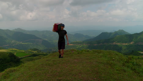 Divertida-Escena-Creativa-De-Un-Hombre-Cargando-Una-Vieja-Televisión-Caminando-Por-La-Montaña-En-Cámara-Lenta