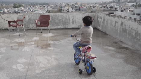 Ein-Asiatischer-Kleiner-Junge,-Der-Auf-Dem-Dach-Fahrrad-Fährt