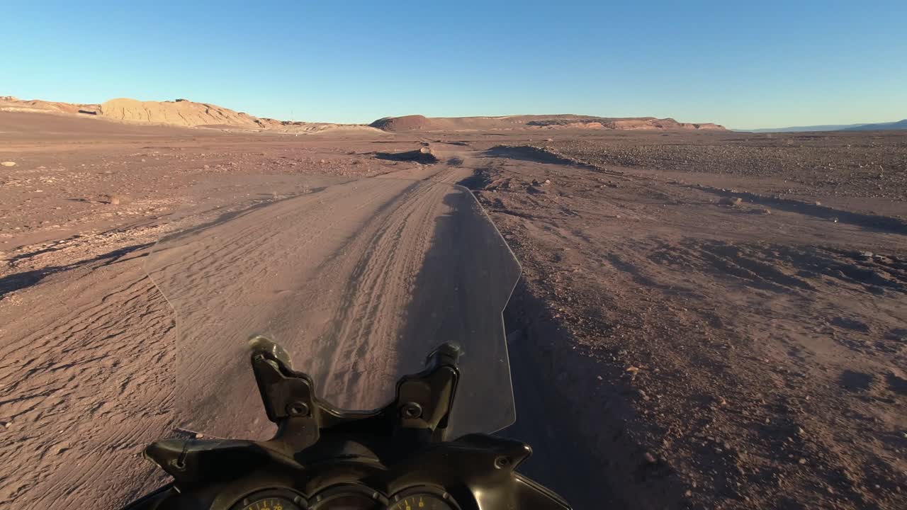 POV: Un motociclista guida su solchi su una strada sterrata accidentata nel deserto in Cile.