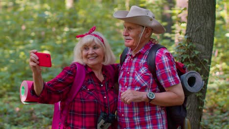 senior grandmother grandfather blogger tourists taking selfie photo portrait on smartphone in forest