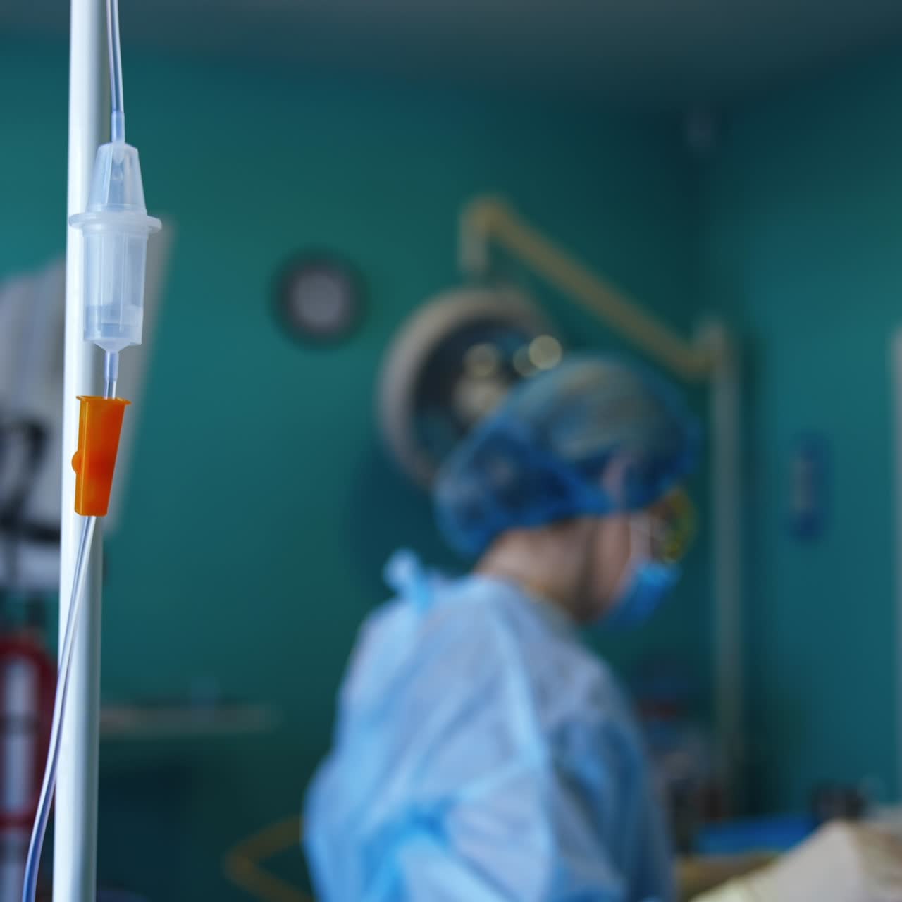 Liquid dripping in the drop counter. Close up. A stand with medicines in the surgery room. Medics perform operation at backdrop