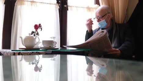 old grandfather reads a newspaper sitting in a cafe old grandfather reads a newspaper sitting in a cafe senor drinks tea and reads the fresh press