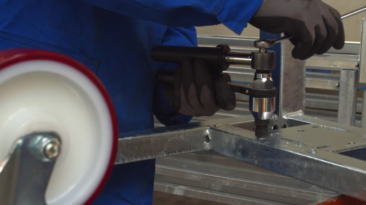 Worker wearing gloves and making screw hole on aluminum frame, static view