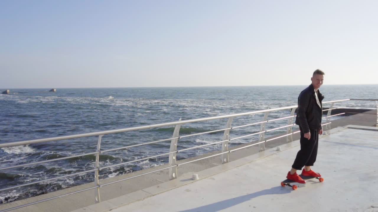 젊은 남자가 그의 롱보드에 스케이팅 웃는다