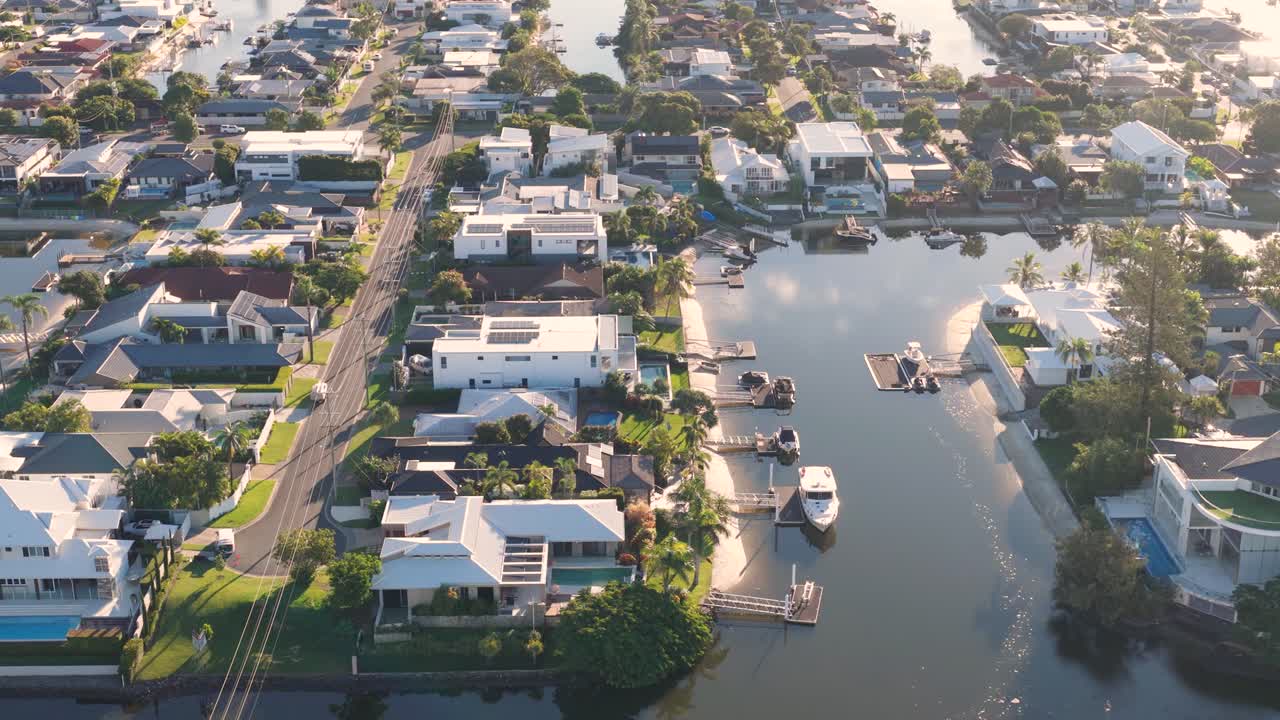 Drone footage captures waterfront homes and canals in Gold Coast, Australia, under warm, natural lighting with smooth camera movement