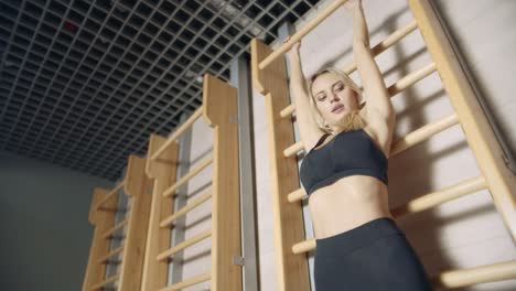 pretty fitness girl pushing up on wall bars in fitness club.