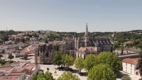 Aerial-pan-shot-capturing-gothic-architecture-Batalha-Monastery-and-townscape,-central-Portugal