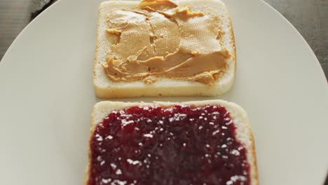 close up view of peanut butter and jelly sandwich in a plate on wooden surface