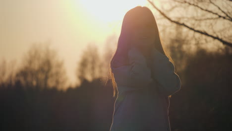 Silhouette-Mädchen-Wedelt-Spielerisch-Mit-Ihren-Haaren-Im-Lebhaften-Sommersonnenuntergang