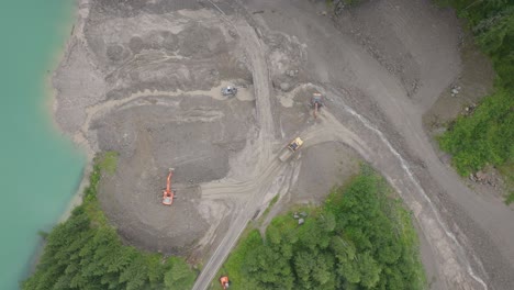 the power of nature is evident as construction equipment maneuvers through a vast mud-covered area, a result of severe weather conditions in the mountainous region