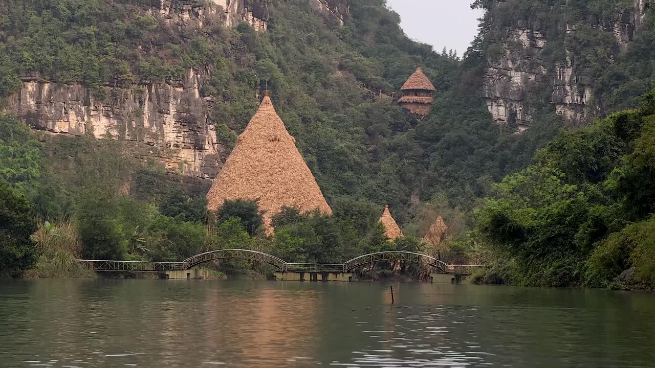 울창한 초록색과 강 사이의 오두막과 다리