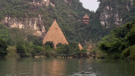 hut and bridge amidst lush greenery and river