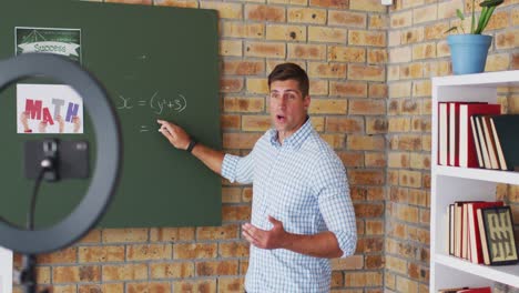 profesor de matemáticas caucásico de pie en el pizarrón dando una lección en línea a la cámara