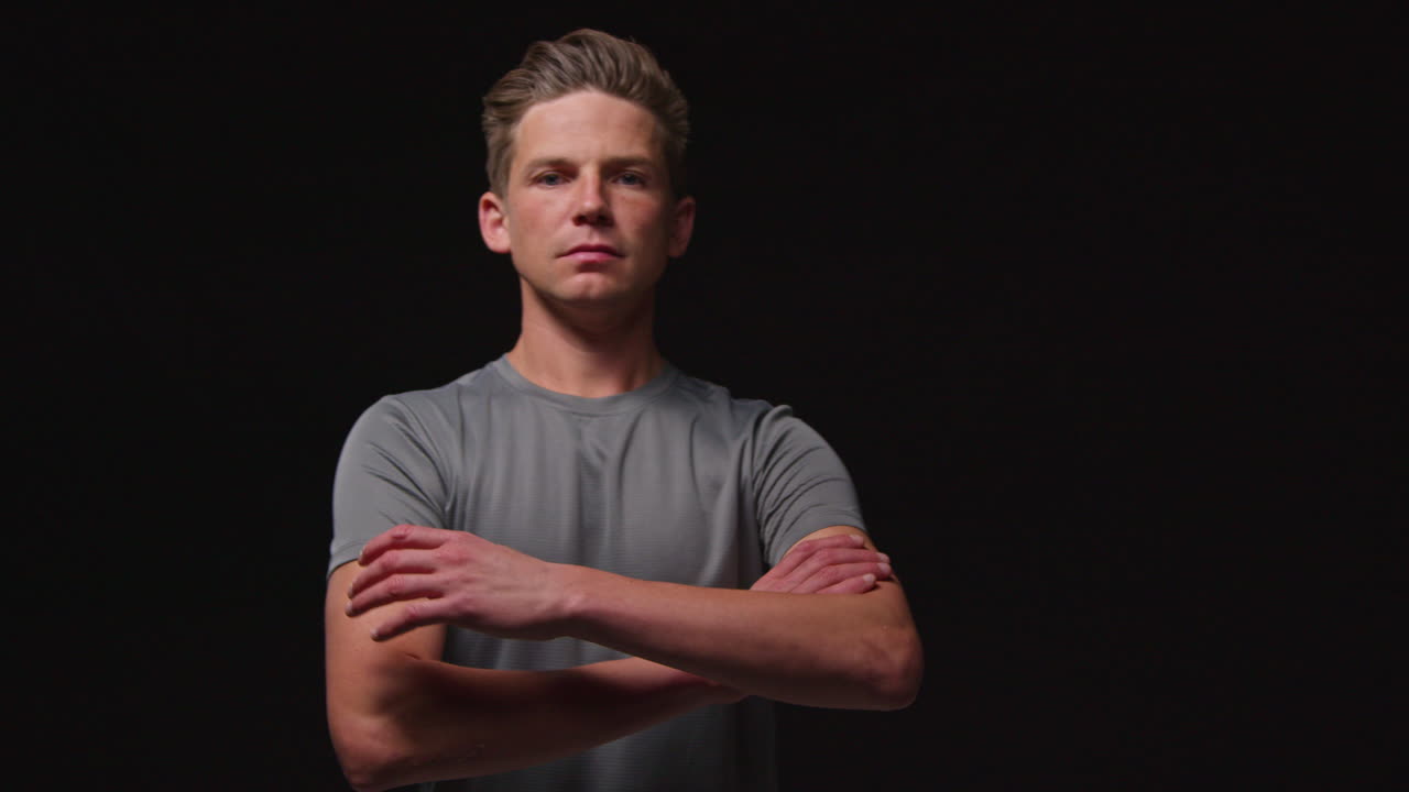 피트니스 옷을 입고 카메라를 향해 고 검은 스튜디오 배경에 대한 스포츠 이벤트 훈련에 초점을 맞추는 심각한 남성 운동 선수의 초상화