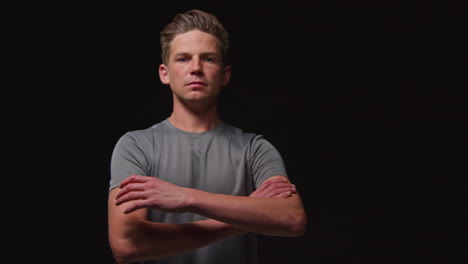 Portrait-Of-Serious-Male-Athlete-Wearing-Fitness-Clothing-Walking-Towards-Camera-And-Into-Focus-Training-For-Sports-Event-Against-Black-Studio-Background