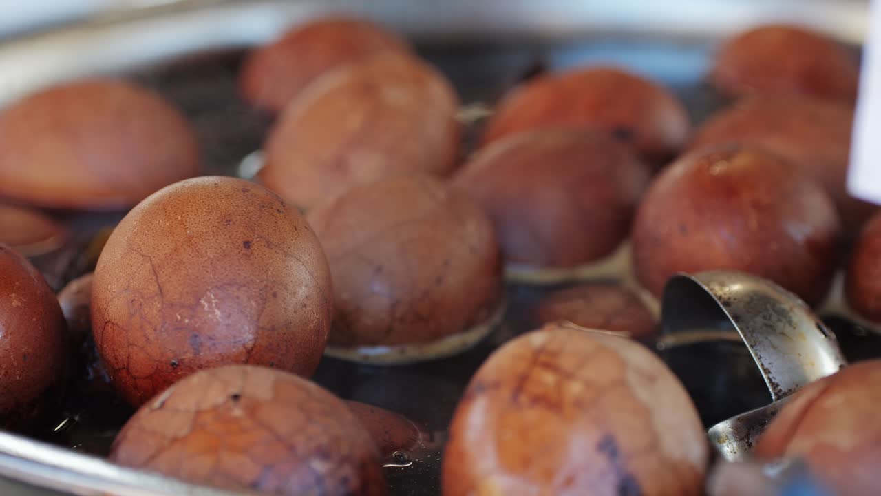 Chinese century eggs or tea egg in boiling water close-up. Chinese egg-based culinary dish made by preserving duck, chicken, or quail eggs in a mixture of clay, ash, salt, quicklime, and rice hulls for several weeks to several months.Korean mayak eggs or mayak gyeran are boiled eggs marinated in a f