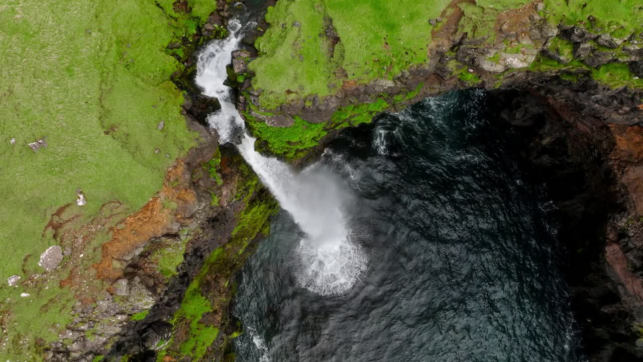 una impresionante vista aérea de la cascada de múlafossur sumergiéndose en el océano