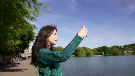 pretty italian woman tourist taking photograph of a park in wimbledon london