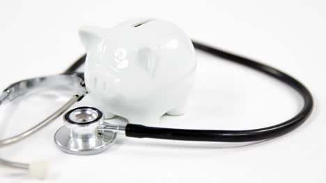 stethoscope and piggy bank on white background