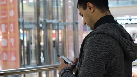 man using phone in a shopping mall