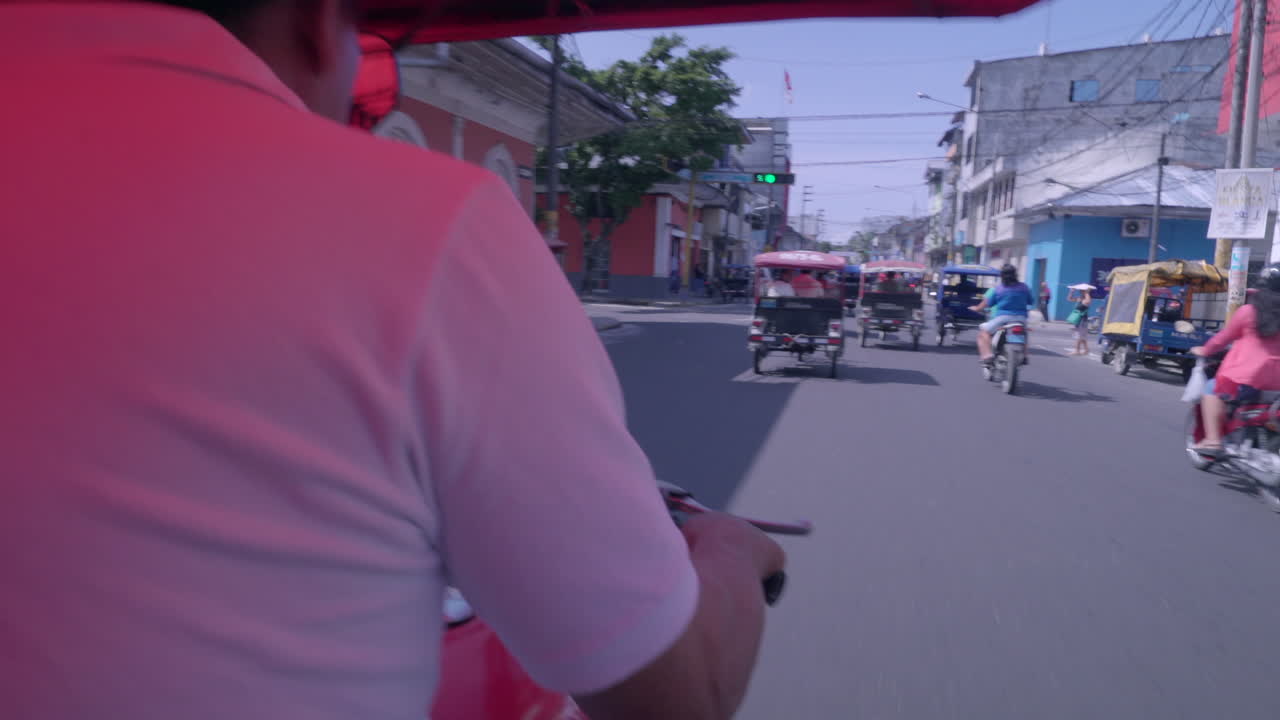 Trike taxi driver rides down busy street on a sunny day.