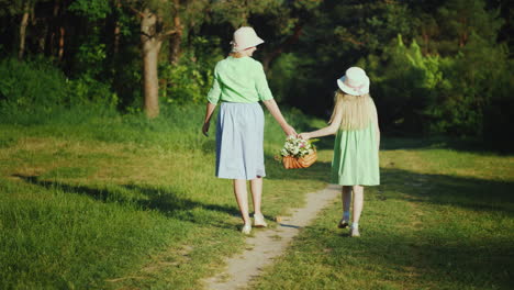 Mutter-Und-Tochter-Gehen-Einen-Waldweg-Entlang-Und-Tragen-Einen-Korb-Mit-Wildblumen