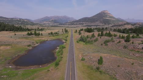 a scenic road stretches through sunlight basin in wyoming, surrounded by mountains and fields
