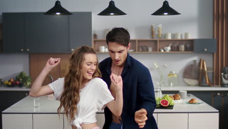 pareja riendo haciendo fiesta de pijama en la cocina. hombre y mujer bailando juntos