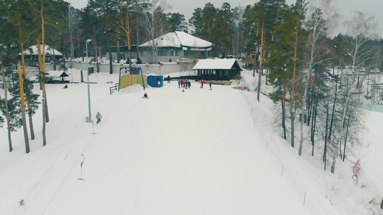 스키복을 입은 사람들은 스노보더가 슬로프 아래로 미끄러지는 것을 보고 있다