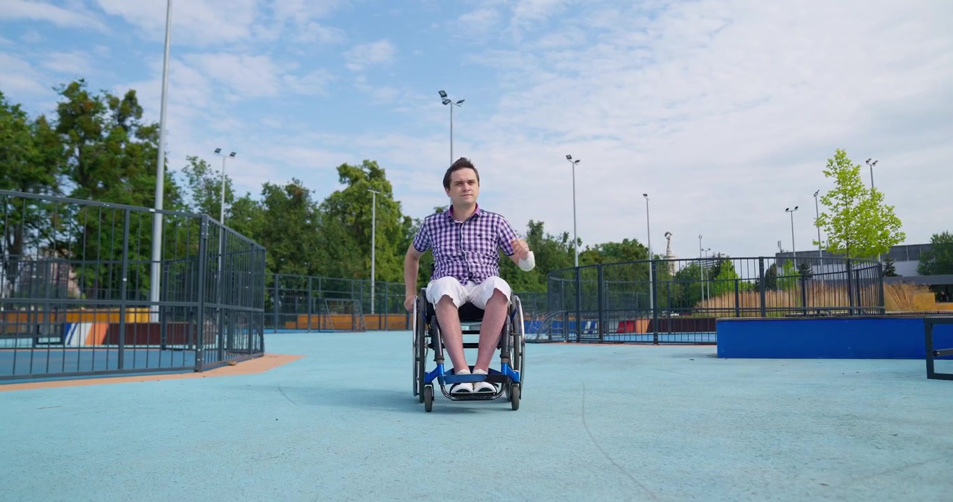 Young Man in Wheelchair Propelling Himself Forward on Outdoor Court